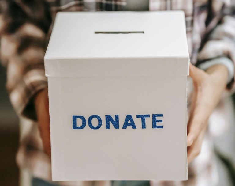 Close-up of a person holding a 'donate' box, encouraging charity and support.
