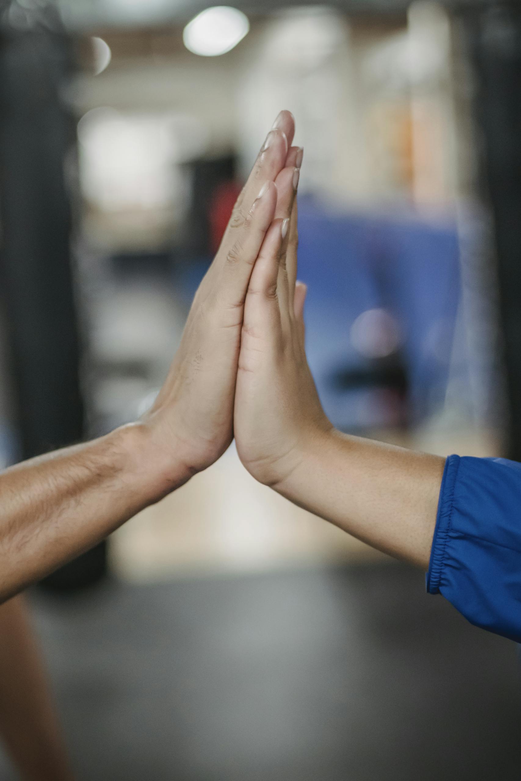Two hands giving a high five, symbolizing teamwork and success, indoors.