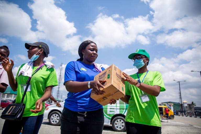 Volunteers work together in an outdoor setting, distributing donation boxes to support their community.